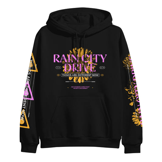 Rain City Drive black pullover hoodie featuring vibrant graphics: large pink and yellow Rain City Drive logo on the front above a gold “Things Are Different Now” banner; sleeves have yellow flowers, text, and geometric shapes.