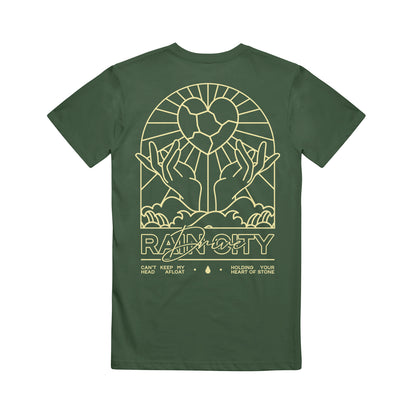 Dark green Rain City Drive T-shirt with a yellow line art design on the back: two hands holding a geometric heart with rays, and below are "Radiocity," "Can't keep my head afloat," and "Holding your heart of stone.