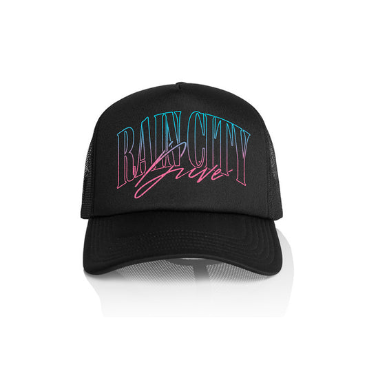 A black Rain City Drive AS Colour foam trucker hat with mesh sides features “RAIN CITY” in large blue and pink neon-style text, with “Grave” in pink cursive below, displayed against a white background.